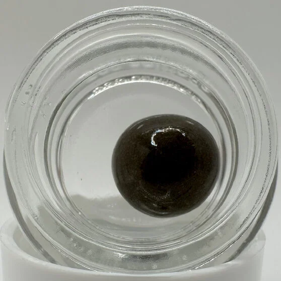 A temple ball, which is a sphere of hash, in a glass container.